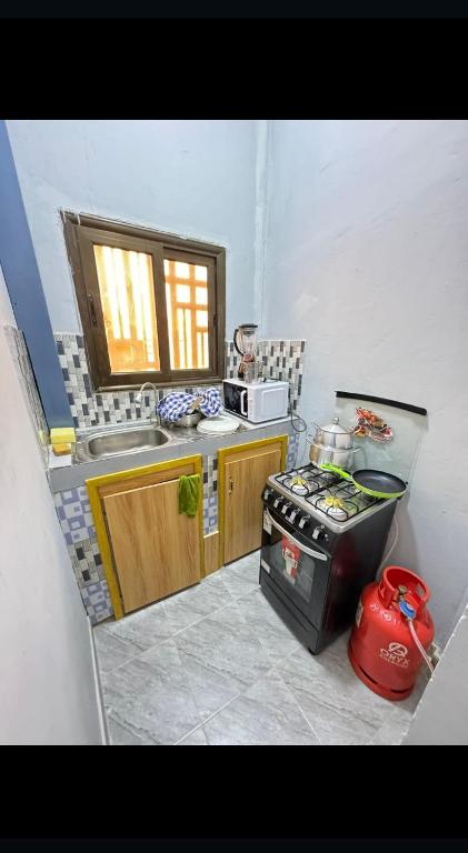 uma pequena cozinha com fogão e micro-ondas em Sanyiri meublée em Ouagadougou