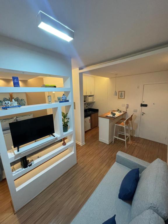 a living room with a couch and a tv on a wall at Flat novo e equipado - Brasília/Sudoeste in Brasília