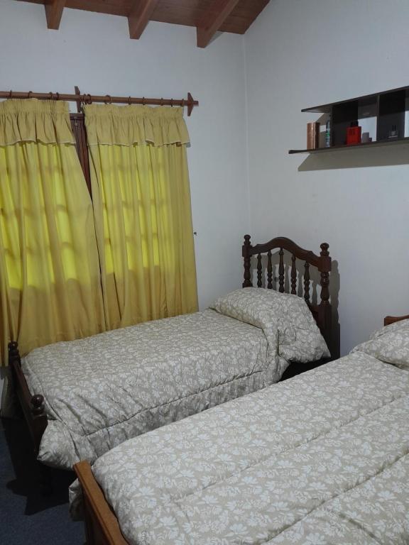 2 camas en un dormitorio con cortinas amarillas en Un ambiente cómodo y placentero, en Guaymallén