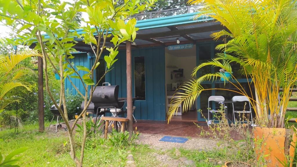 a blue house with a black chair and some trees at Tiny House Serendipia - Caserío El Puente -Villeta in Villeta