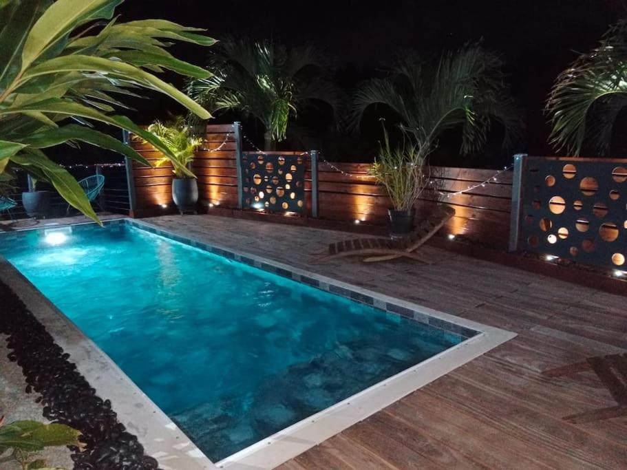 a swimming pool in a backyard with a wooden deck at T2 Beausoleil in Les Abymes
