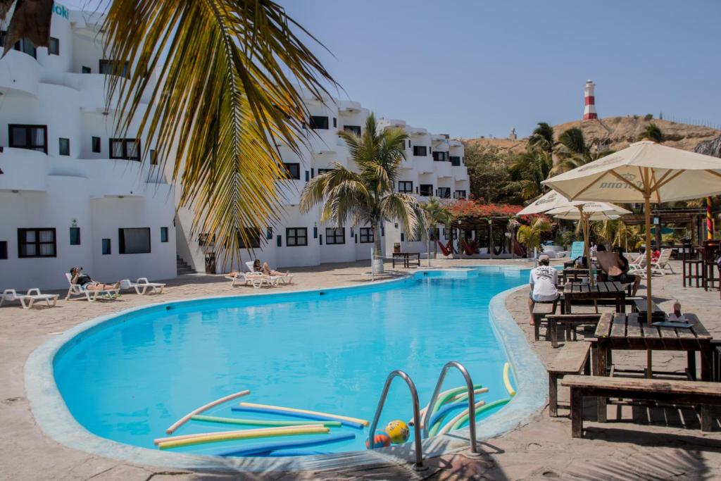 una piscina con sillas y sombrillas junto a un hotel en Loki del Mar en Máncora