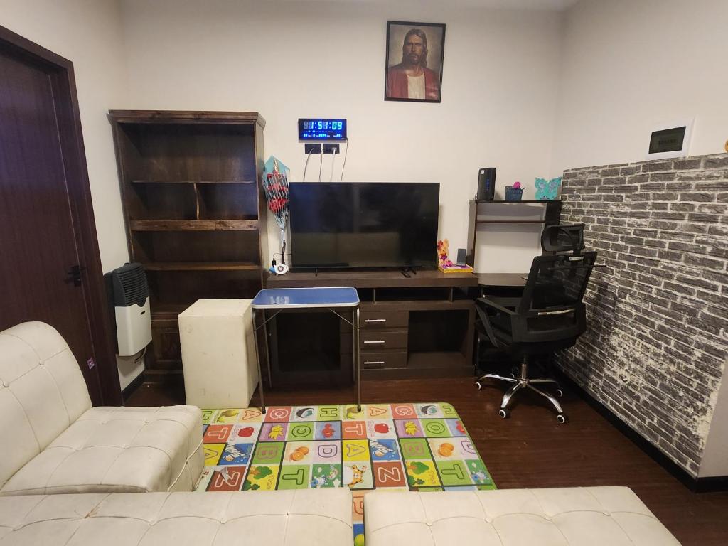 een woonkamer met een bank en een bureau met een televisie bij Hermoso y céntrico in Cochabamba