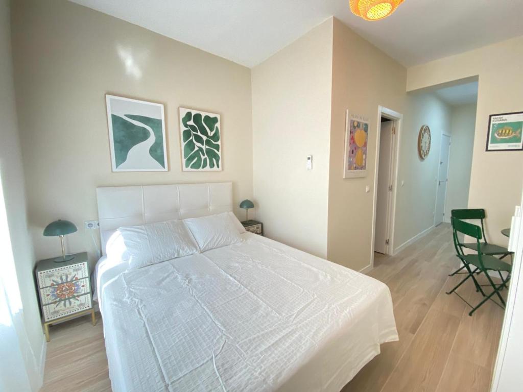 1 dormitorio con 1 cama blanca, mesa y sillas en ESTUDIOS GRAN VÍA, en Madrid