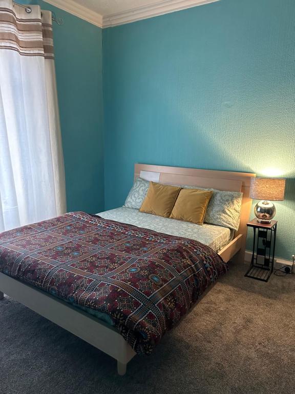 a bedroom with a bed with a blue wall at mid street in Bathgate