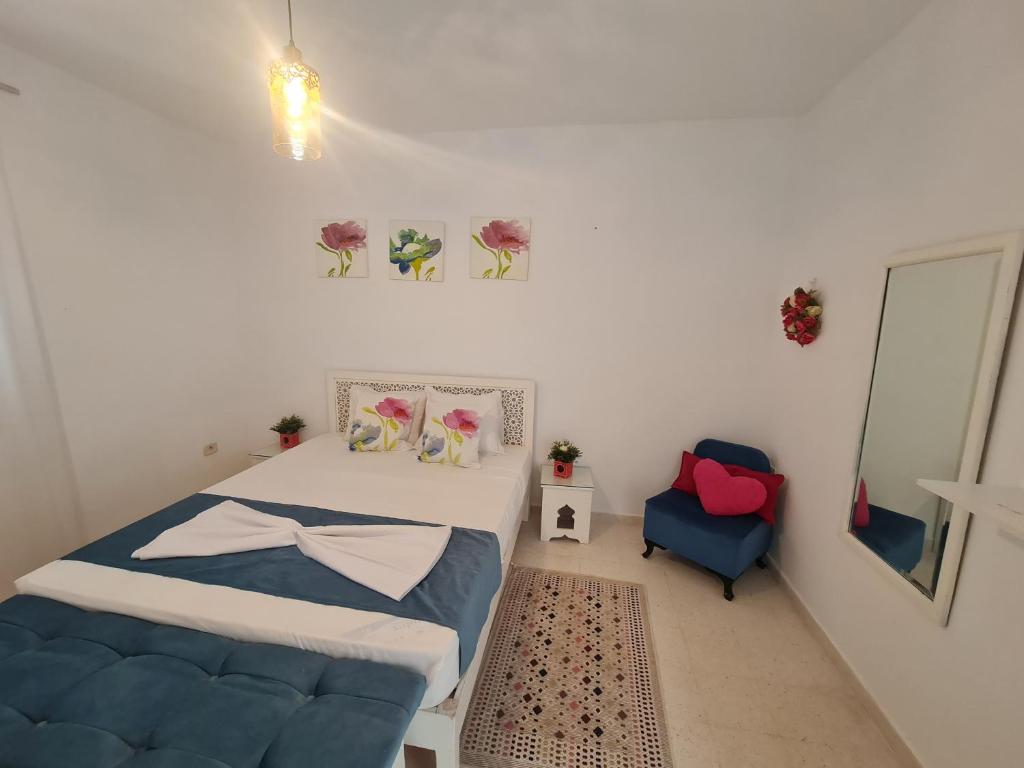 a bedroom with a bed and a blue chair at Dar selim in Midoun