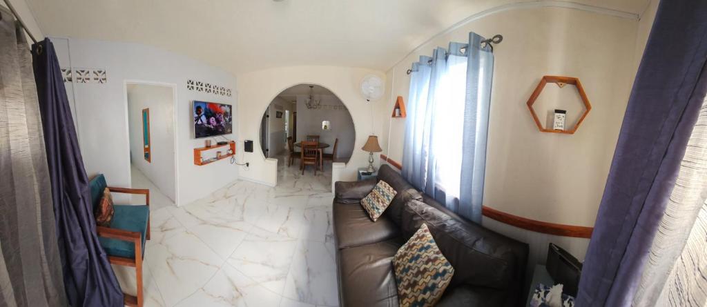 a living room with a leather couch and a hallway at Gloria's Hideaway in Christ Church