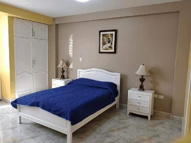 a bedroom with a blue bed and two night stands at HOSPEDAJE VALERY in Trujillo