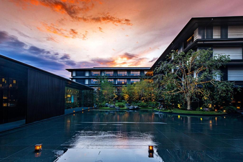 a pool in front of a building with a sunset at HOTEL THE MITSUI KYOTO, a Luxury Collection Hotel & Spa in Kyoto