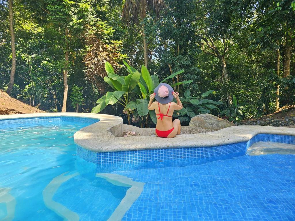 Una donna in bikini seduta accanto alla piscina di Cabanas El Toche a Santa Marta