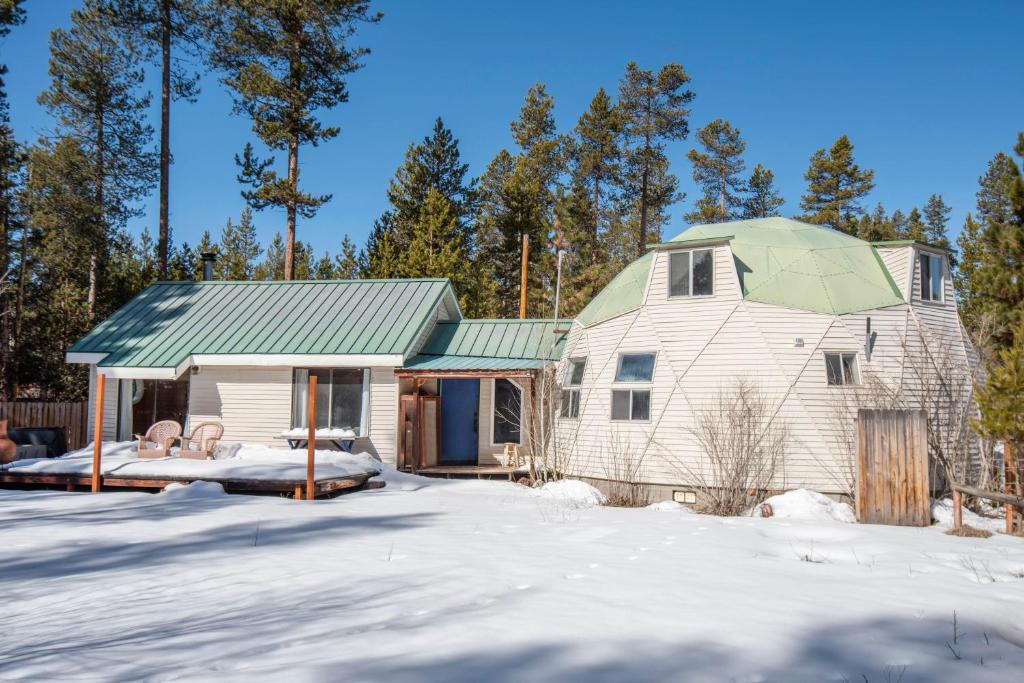 una casa blanca con techo verde en la nieve en Dome Home, en La Pine