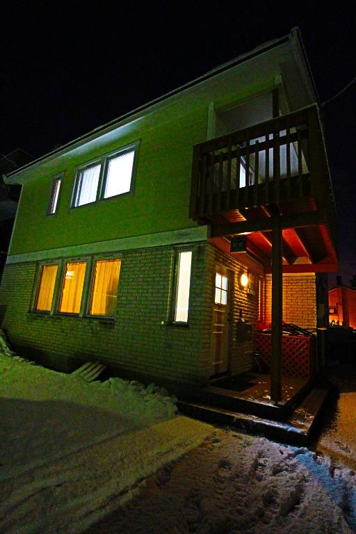 a green brick house at night with snow on the ground at ゲストハウス樹舎 in Minami-jūichijō