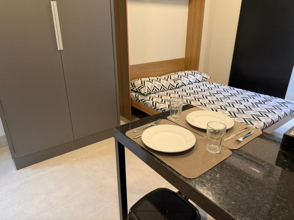 Cette chambre comprend une table avec des assiettes et des verres. dans l'établissement Studios Soho Bongiovani, à Presidente Prudente