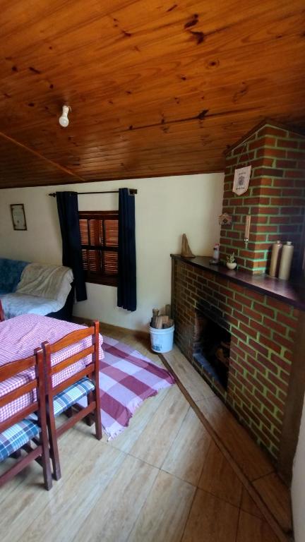 un soggiorno con camino in mattoni e letto di Casa da Cíntia a Visconde De Maua