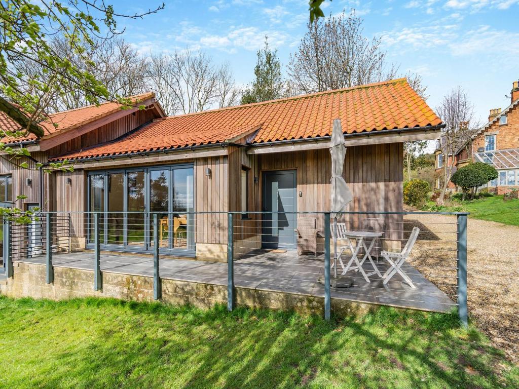 a wooden house with a deck and a table at The Cedars Cottage 2 - Uk46778 in Cloughton