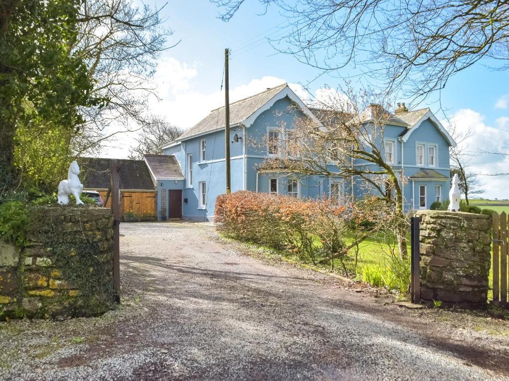 a blue house with a white cat on a stone fence at Gymmin House in Pendine