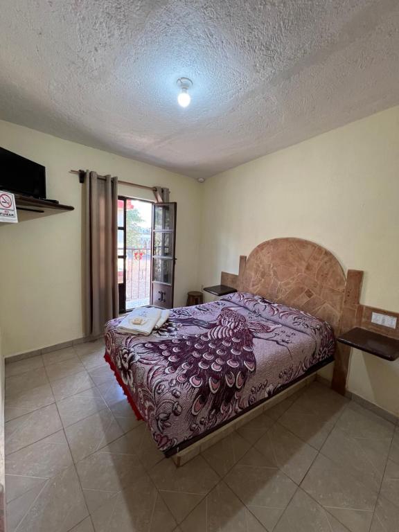 een slaapkamer met een bed met een paars dekbed bij Hotel Casa De Los Abuelos in Bernal