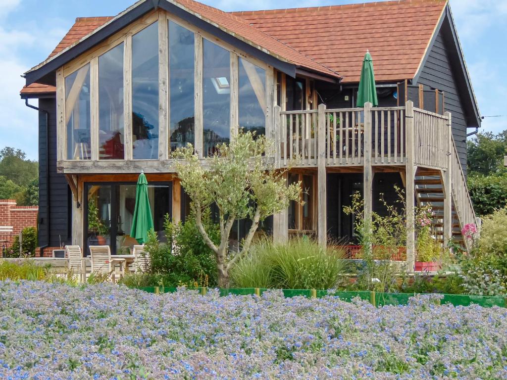 a house with windows and a garden with purple flowers at Country Escape At The Granary in Copford