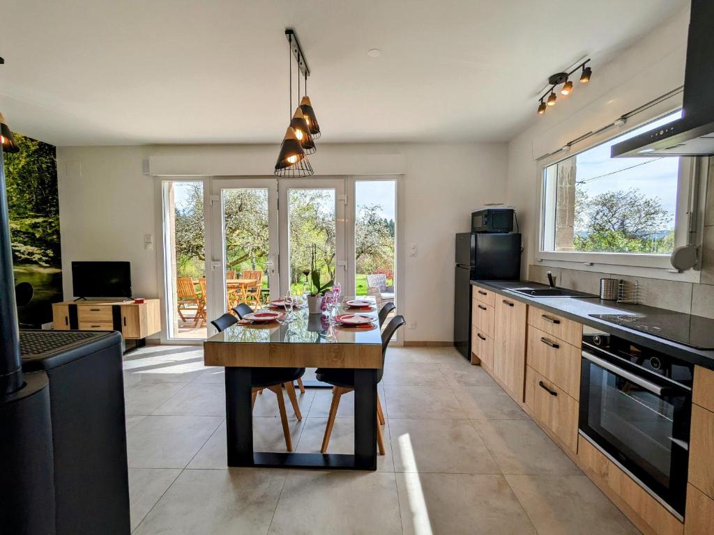 - une cuisine avec une table en bois et des fenêtres dans l'établissement Maison neuve et paisible avec étang privé, terrasse et randonnées aux portes du Pays de Salm - FR-1-589-635, à Moyenmoutier