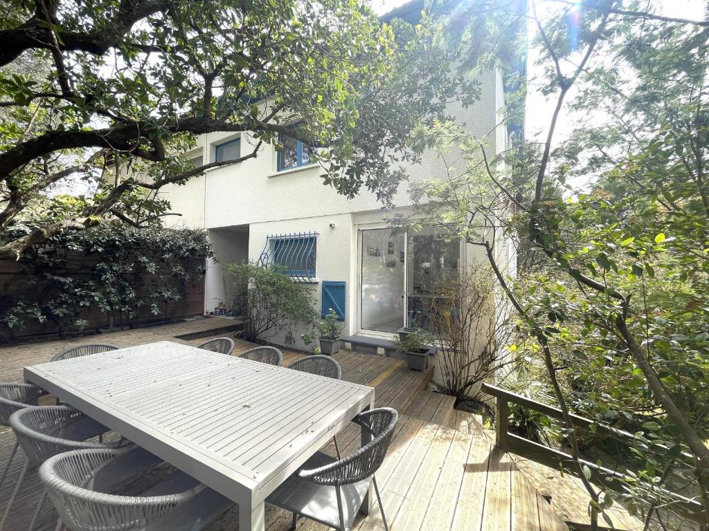 une terrasse en bois avec une table et des chaises blanches dans l'établissement Maison familiale à Arcachon : 3 chambres, jardin sous les pins, WIFI FIBRE, proche plage et centre - FR-1-420-145, à Arcachon