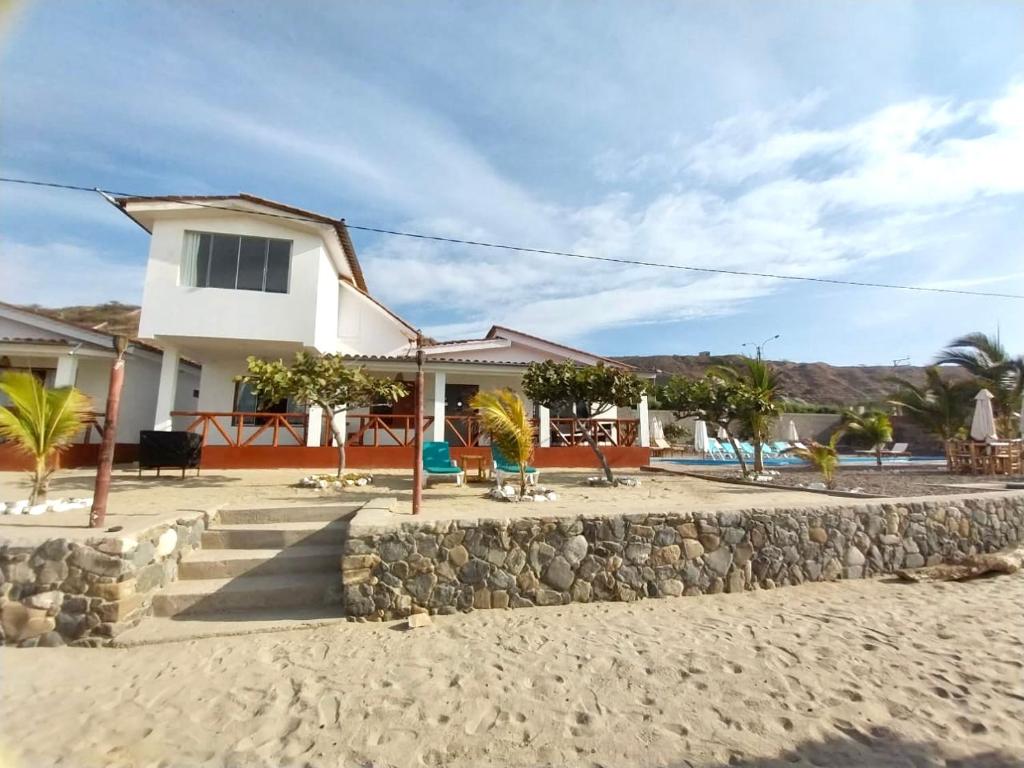 a house on the beach with a stone wall at Casuarinas del Mar Chalet Playa Caballito de Mar in Canoas De Punta Sal