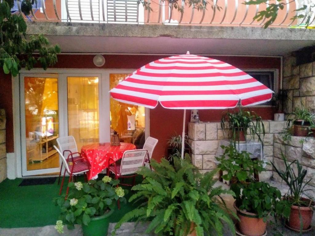 un parasol rouge et blanc, une table et des chaises dans l'établissement Ferienwohnung für 4 Personen ca 65 qm in Zelenka, Dalmatien Mitteldalmatien, à Makarska