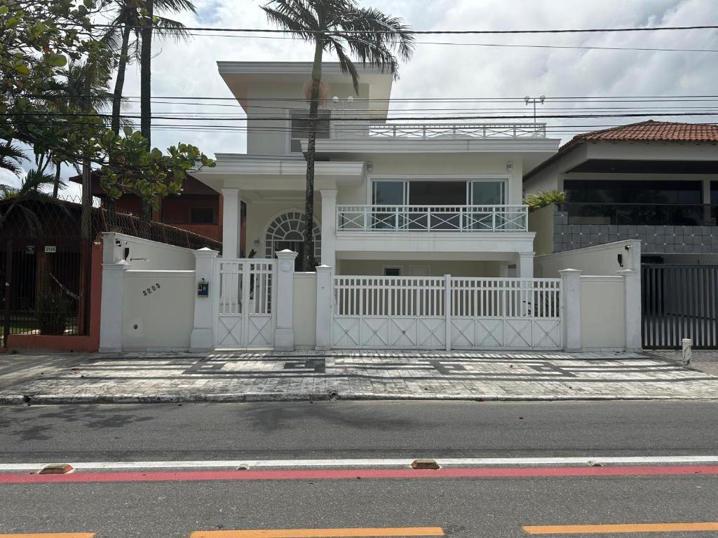 a white fence in front of a house at Enseada Premium Suítes in Guarujá