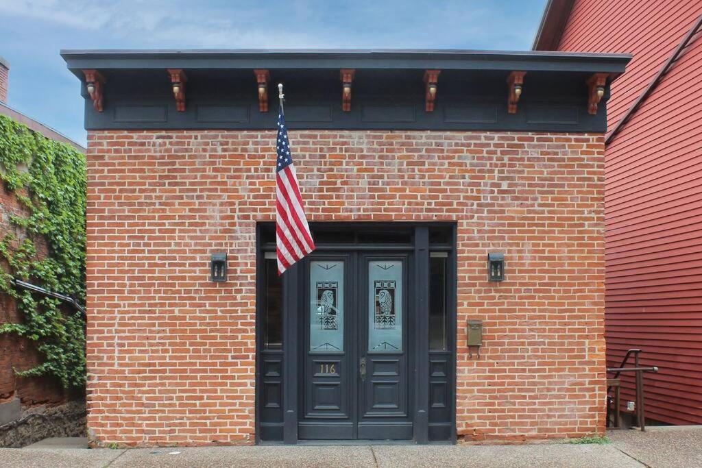 a brick building with an american flag above a door at The Owl House in Galena