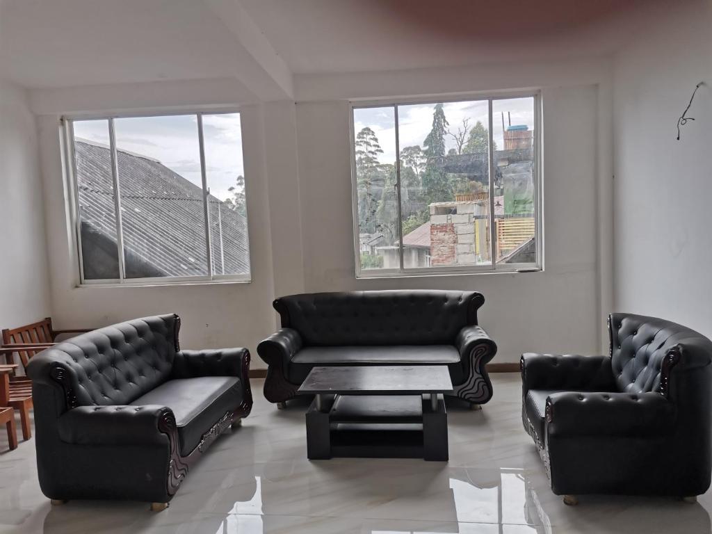 a living room with couches and a table and windows at Traveler's Choice in Nuwara Eliya