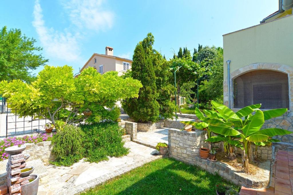 een tuin met bomen en planten voor een huis bij Ferienwohnung für 4 Personen ca 45 qm in Fažana-Surida, Istrien Istrische Riviera in Valbandon