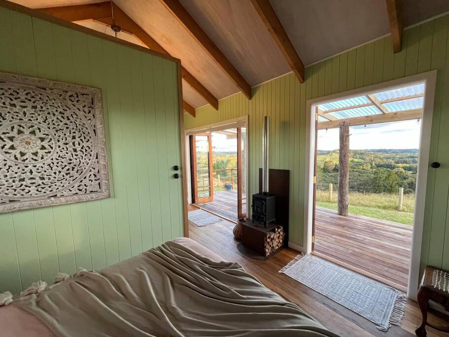 - une chambre avec un lit et une porte coulissante en verre dans l'établissement Romantic hilltop hideaway - Skyview Cottage, à Dairy Flat
