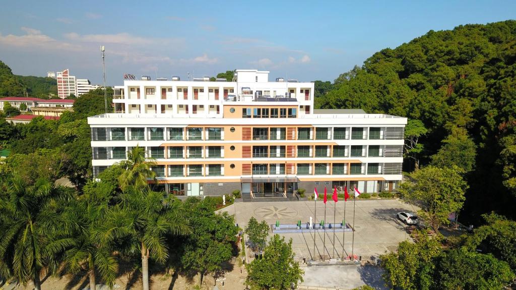 a large white building with palm trees in front of it at Hanvet Hotel Do Son in Ðố Sơn