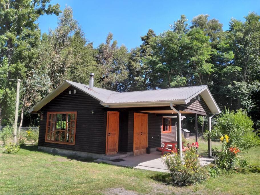 a small cabin with a porch in a yard at Cabaña Palual in El Manzano