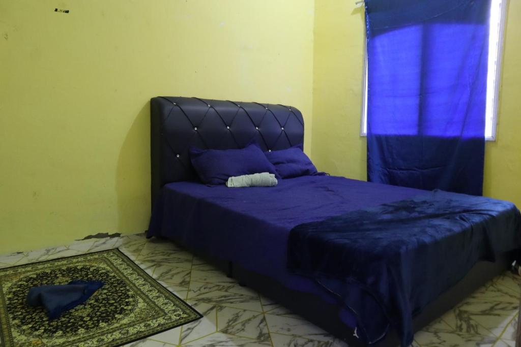 - une chambre avec un lit doté de draps violets et une fenêtre dans l'établissement Singgahan Cinta Iris, à Kampong Gong Merbau