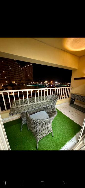 - Balcón con mesa y 2 sillas de mimbre en شالية VIP باهرامات بورتو السخنة en Ain Sokhna