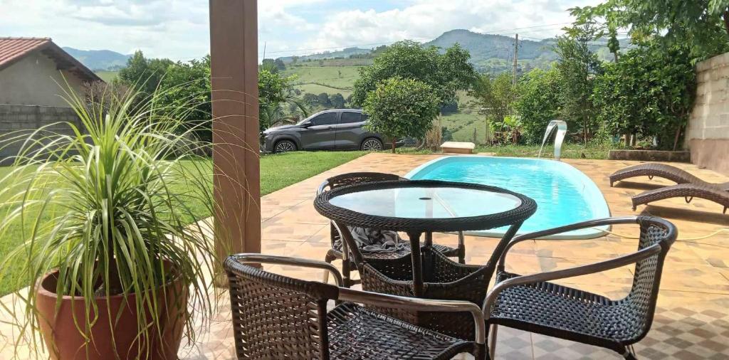 d'une terrasse avec une table et des chaises à côté de la piscine. dans l'établissement Recanto São Gabriel Socorro/SP chácara com linda Vista, à Socorro