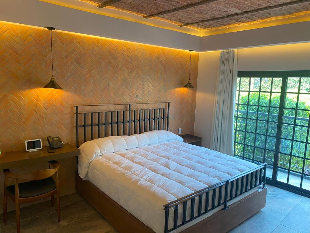um quarto com uma cama, uma secretária e uma janela em Hotel Boutique Divino Sol em León