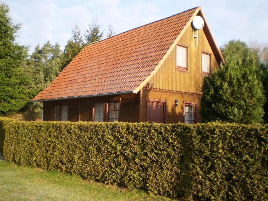 a house with a brown roof behind a hedge at Ferienwohnung für 4 Personen ca 60 qm in Nossentiner Hütte, Mecklenburg-Vorpommern Mecklenburgische Seenplatte in Nossentiner Hütte