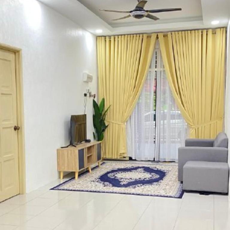 a living room with a couch and a television at Nuria Padang Serai Homestay in Padang Serai
