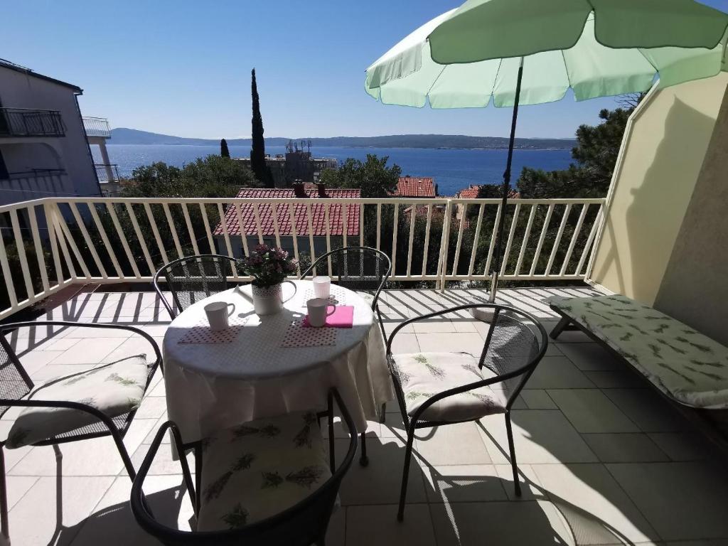 a table and chairs on a balcony with an umbrella at Ferienwohnung für 5 Personen ca 65 qm in Selce bei Crikvenica, Kvarner Bucht Crikvenica und Umgebung in Selce