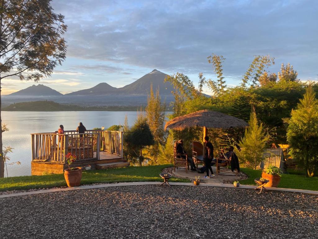 a group of people sitting under an umbrella near a lake at Ruhondo Beach Resort in Ruhengeri
