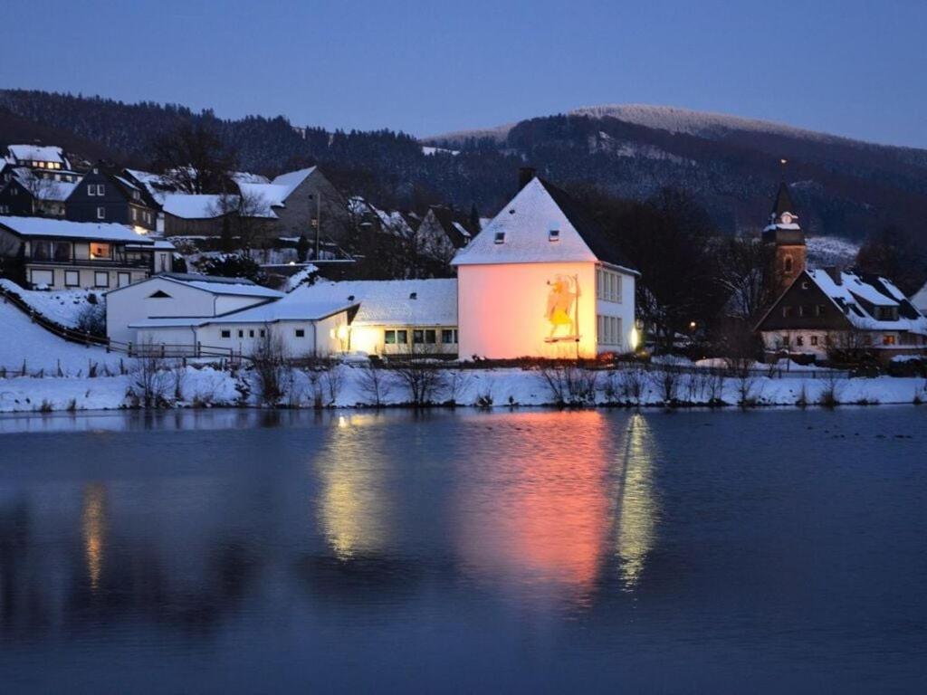 un edificio iluminado junto a un cuerpo de agua en Modern retreat by the lake, en Olsberg
