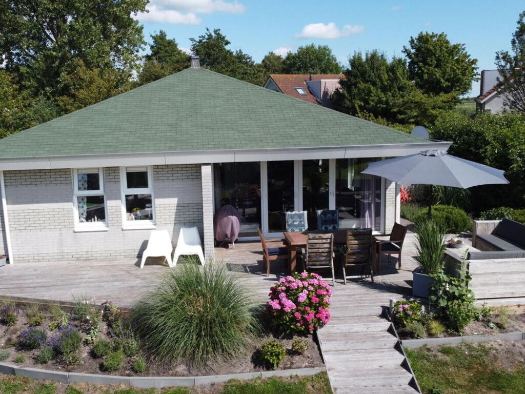 a house with a patio with chairs and an umbrella at Friesche Zusje on the IJsselmeer in Makkum