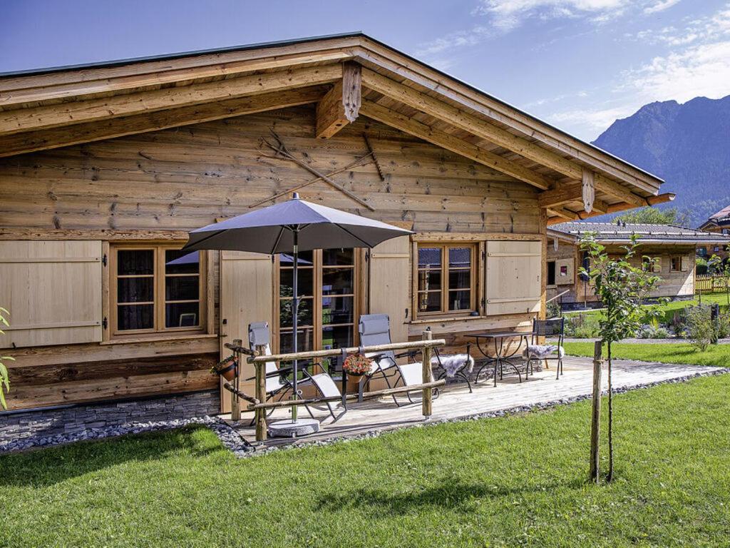 a log cabin with a table and an umbrella at Alpglück Chalet Modern retreat in Oberstdorf