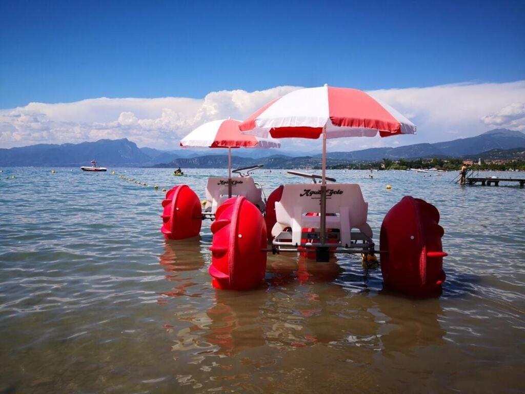 un bateau avec des chaises et des parasols dans l'eau dans l'établissement Lugana Residence We LAKE it, à Peschiera del Garda
