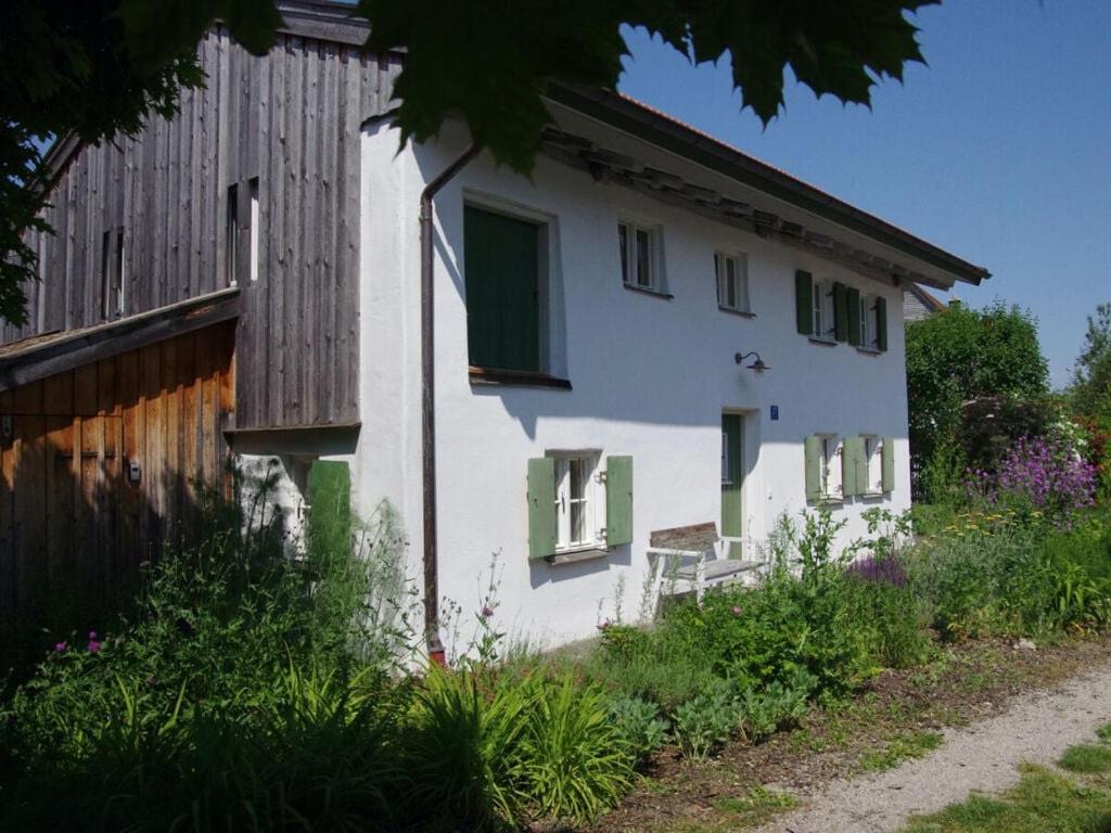 ein weißes Haus mit grünen Rollläden und einer Bank im Freien in der Unterkunft Fisherman's House Modern Retreat in Dießen am Ammersee