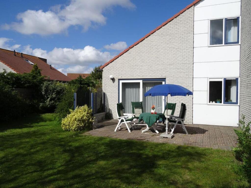 a patio with a table and chairs and an umbrella at Summer Melody Comfortable holiday residence in Julianadorp