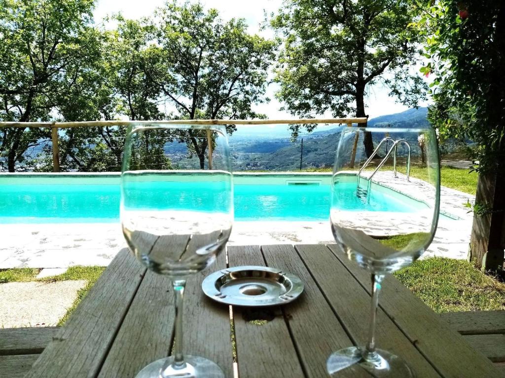 two wine glasses sitting on a wooden table near a swimming pool at Ferienhaus mit Privatpool für 2 Personen 2 Kinder ca 70 qm in Uzzano, Toskana Provinz Pistoia in Uzzano