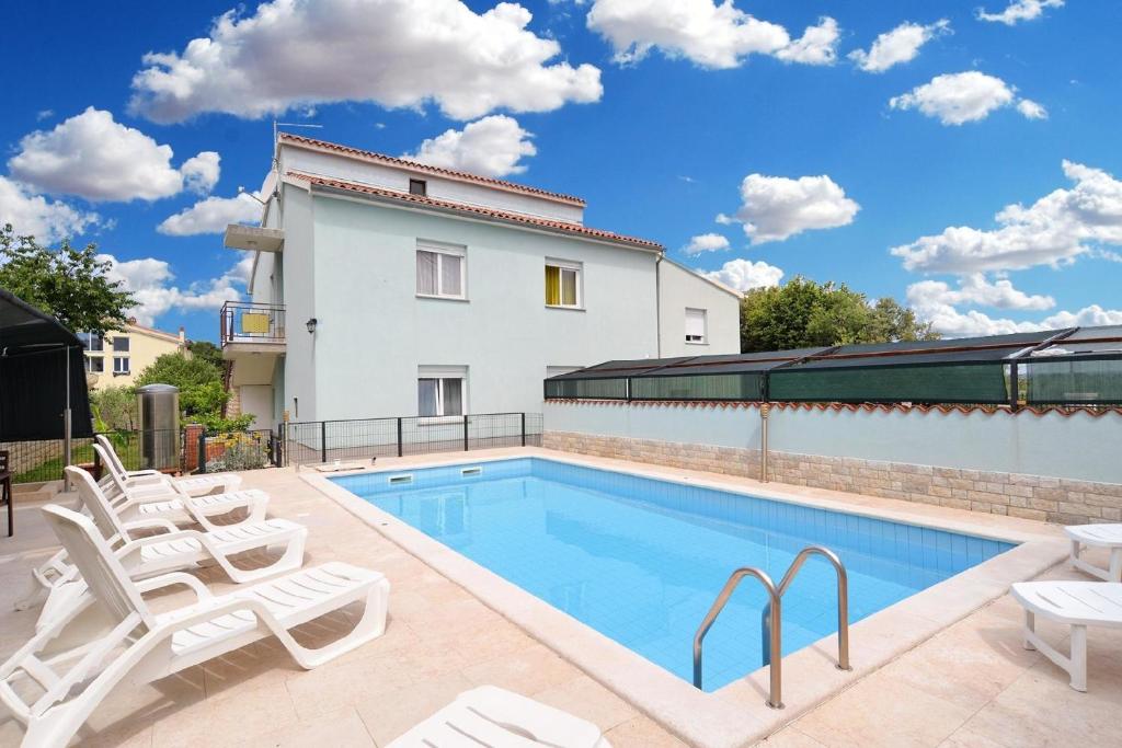 - une piscine avec des chaises et une maison dans l'établissement Ferienwohnung für 6 Personen ca 71 qm in Pula-Fondole, Istrien Istrische Riviera, à Štinjan