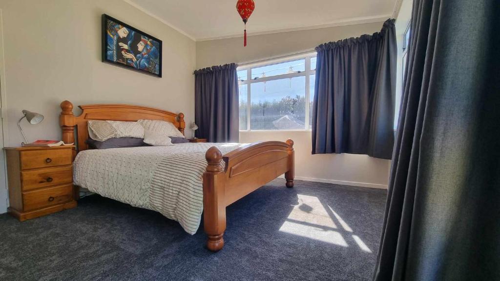 1 dormitorio con cama de madera y ventana en 135 On Seaview Parpaparaumu Beach, en Paraparaumu